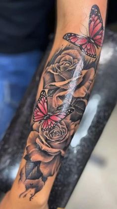 a woman's arm with roses and butterflies on it, in black and grey