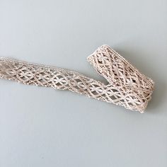 two pieces of white lace sitting on top of a gray surface with one piece cut out