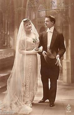 an old photo of a man and woman in wedding attire standing next to each other