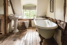 an old fashioned bathtub is in the middle of a bathroom with wood flooring