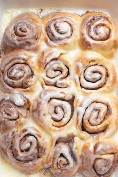 a baking dish filled with cinnamon rolls covered in icing