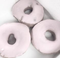 three glazed donuts sitting on top of a white counter next to each other in a box