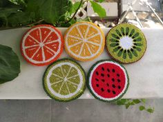 four pieces of fruit are sitting on a table next to some plants and leaves,