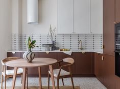 a kitchen with a table and chairs next to an oven in the middle of it