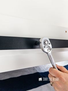 a person holding a wrench in front of a black and white striped wallpaper