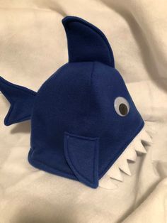 a blue stuffed shark with large teeth on a white sheet