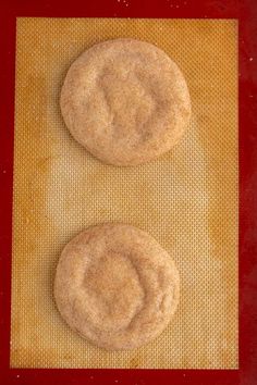 two cookies sitting on top of a piece of waxed paper next to each other