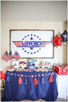 a table topped with cake and balloons in front of a large sign that says maverich