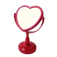 a red heart shaped mirror sitting on top of a stand