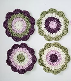 four crocheted flower coasters on a white surface