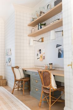 a desk with two chairs in front of it and shelves on the wall behind it