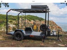 a black trailer parked on the side of a hill with a mountain in the background