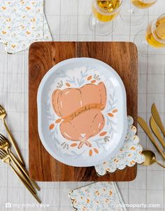 a white plate with an orange design on it sitting on top of a wooden cutting board