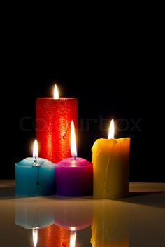 three lit candles sitting next to each other in front of a black background with reflections on the floor