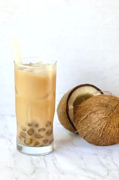 a drink with a straw in it next to a coconut