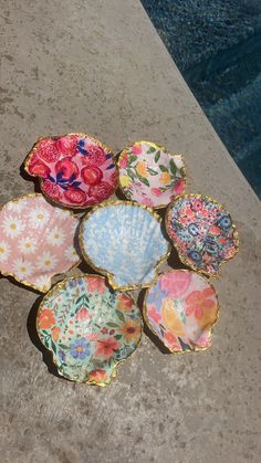 six colorful plates sitting on the ground next to a swimming pool