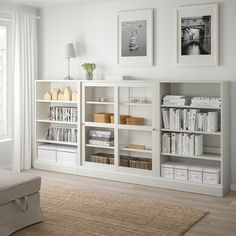 a living room filled with white furniture and bookshelves next to a large window