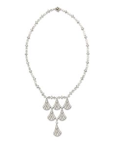 a white necklace with three drops and diamonds on the clasp, hanging from a silver chain