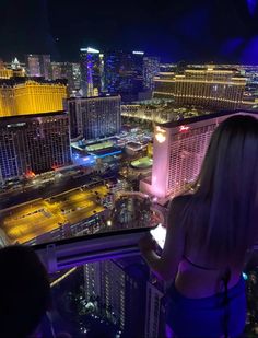 a woman standing on top of a tall building looking at the city lights in las vegas