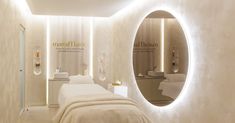 a spa room with white walls and lights on the wall, an oval mirror in the middle