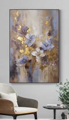 an abstract painting with blue and gold flowers on the wall next to a white chair