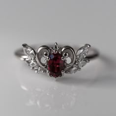 Inspired by Neo-Queen Serenity's crown from the Sailor Moon anime that I watched religiously as a child, this ring is both delicate and regal. The center garnet is set inside a golden heart with a tiny fleur-de-lis crown and diamond wings. CUSTOMIZE GEMSTONES ✶ solid 14 karat recycled yellow, white, or rose gold✶ band measures 1.6mm wide x 1.4mm thick✶ center stone: 0.33 carat, VS clarity, AA grade natural rhodolite garnet✶ accent stones are 0.22 total carat weight VS clarity lab-grown diamondsT Vintage Gothic Wedding Rings, Gothic Engagement Ring Victorian, Goth Engagement Ring, Alt Wedding Rings, Wed Rings, Victorian Wedding Ring, Magical Elements, Sailor Moon Anime, Beau Crochet