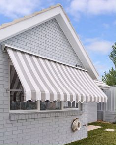 an awning on the side of a house in front of a white brick building