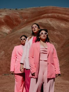 three women in pink suits and sunglasses standing next to each other