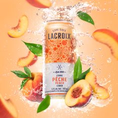 a can of peach cider surrounded by sliced peaches and leaves in the water