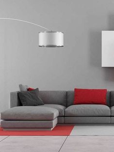 a modern living room with grey couch and red throw pillows on the floor in front of a white wall