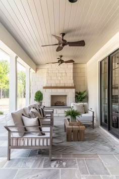 an outdoor living area with couches, tables and ceiling fans