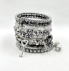 This stacked silver bracelet is made on memory wire to wrap around your wrist 11 times. It is strung with crystals, Czech beads, glass beads, metal beads, hematite, and finished perfectly with multiple handmade crystal and pearl drops on each end and 2 silver charms: a key and a lock. It's a perfect layered look filled with crystals and bling.  ★ Return to my main shop page here for more inventory ★ www.etsy.com/shop/bridgetollbeading ★ Read my FAQ's below and if you have any further questions p Silver Hand Wrapped Beaded Bracelets For Party, Silver Beaded Wrap Bracelet For Party, Silver Hematite Beaded Stretch Bracelet, Silver Stretch Bracelet With Hand Wrapped Round Beads, Silver Hematite Crystal Bracelet Gift, Silver Hematite Bracelets With Silver Beads, Silver Hematite Bracelet With Silver Beads, Stretch Beaded Bracelets Diy, Silver Bracelet Stack