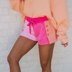 Be Comfortable And Stylish With These Pink And Orange Colorblock Active Shorts. Featuring A Drawstring Waistband, Button Snap Detailing On Sides, And Back Pocket, Plus A Built In Short Lining, They Are Perfect For Your Active Lifestyle! 100% Polyester Inseam: 1.75" Model Is 5'4" With A 25" Waist And 38" Hips And Wearing A Small. Pink Cotton Bottoms With Button Closure, Pink Summer Bottoms With Buttons, Pink Buttoned Summer Bottoms, Pink Summer Bottoms With Button Closure, Casual Spring Shorts With Contrast Color, Trendy Pink Bottoms With Button Closure, Pink Color Block Bottoms For Beach, Pink Color Block Bottoms For Spring, Pink Color Block Beach Bottoms