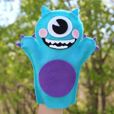 a hand holding up a blue monster mitt