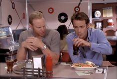 two men sitting at a table eating food