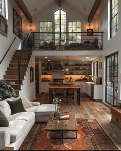 a living room filled with furniture and lots of windows next to a stair case in front of a kitchen