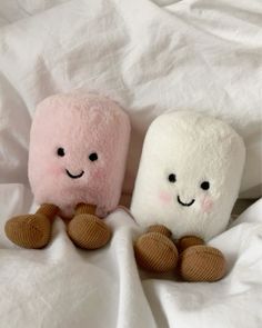 two stuffed animals sitting on top of a bed