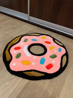 a pink donut rug on the floor with multicolored sprinkles