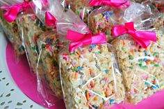 rice krispy treats are wrapped in cellophane and tied with pink bows on a pink plate