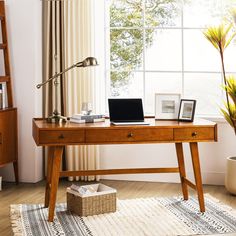 a wooden desk with a laptop on top of it next to a potted plant