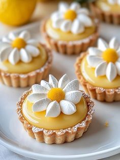 small lemon tarts decorated with flowers on a white plate