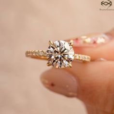 a woman's hand holding an engagement ring with a diamond on top and side