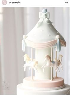 a carousel cake with white frosting and pastel pink icing, topped with ponies