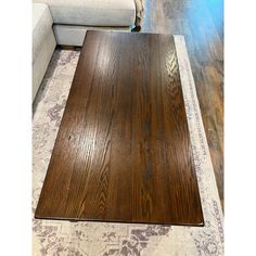 a large wooden table sitting on top of a rug in front of a white couch