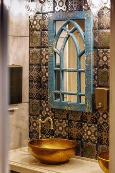 a bathroom sink with a gold bowl underneath it and an ornate mirror above the sink