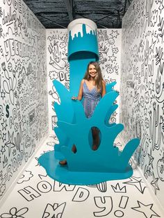 a woman is sitting on a giant blue object in the middle of a room with graffiti all over it