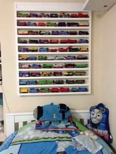 a child's bed with thomas the train comforter and toy cars on it