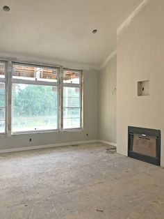 an empty living room with a fireplace and large windows in the middle of the room