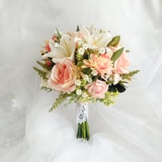 a bridal bouquet with pink and white flowers on a white clothed background,