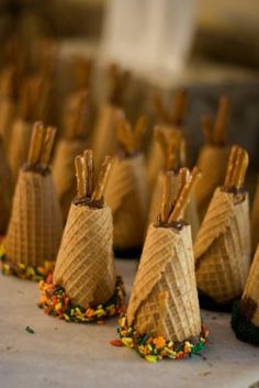 several cones are lined up on the ground with candy coming out of them and sprinkles all around them